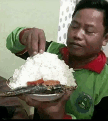 a man in a green shirt is holding a plate of food in his hand .