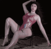 a woman in a red bodysuit is sitting on a chair in the sand