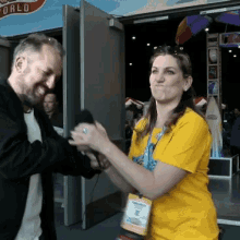 a woman in a yellow shirt is being interviewed by a man in front of a sign that says world