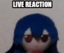 a stuffed animal with blue hair and red eyes is sitting on a table with the words `` live reaction '' above it .