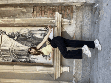 a woman laying on the ground in front of a wall