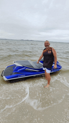 a man stands next to a yamaha jet ski