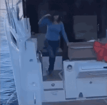 a woman in a blue sweater is standing on a boat