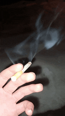 a person is holding a cigarette in their hand