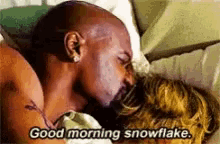 a man and a woman are laying in bed and the man says good morning snowflake .