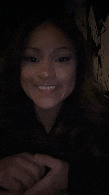 a woman is smiling in a dark room with a black background