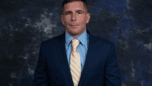 a man in a suit and tie is standing in front of a blue backdrop