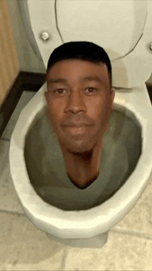 a man 's head is sticking out of a toilet seat