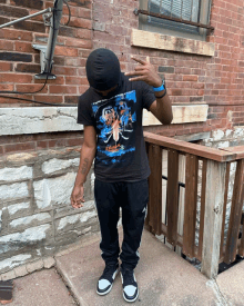 a man standing in front of a brick wall wearing a black t-shirt with a spider on it