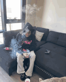 a person sitting on a couch smoking a cigarette and wearing a pink panther sweatshirt