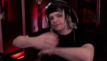 a man with dreadlocks is wearing headphones and a headband and is dancing in a dark room .