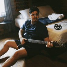 a man sitting on the floor holding a guitar that says mesanello