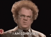 a man with curly hair and glasses is standing in front of a microphone and says `` i am confused '' .