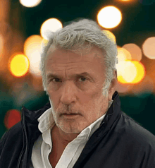 a man with gray hair and a beard is wearing a black jacket and a white shirt