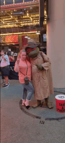 a woman stands next to a statue of teenage mutant ninja turtles