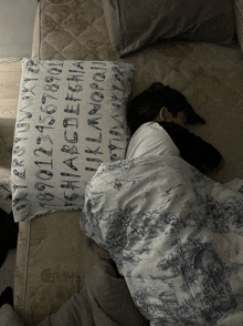 a person laying on a bed with a pillow that says alphabet