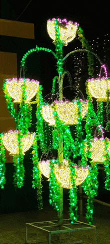 a tree decorated with green and yellow lights and purple flowers