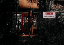 a woman in a dress is walking through a doorway with a sign that says delivery entrance .