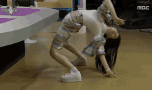 a woman is doing a handstand on the floor in front of a mbc logo .