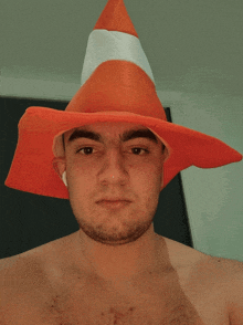 a man without a shirt is wearing an orange cone hat