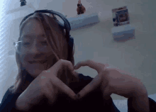 a girl wearing headphones makes a heart with her hands