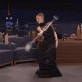 a woman in a black dress is dancing with a mop in her hand