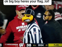 a man wearing a nebraska shirt stands in front of a referee