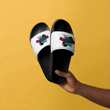 a person is holding a pair of black and white slides with a logo that says " sticky rubber "