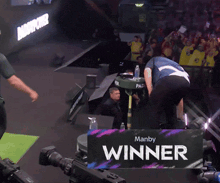 a man is standing in front of a manby winner sign