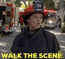 a woman in a fireman 's uniform is standing in front of a fire truck with the words walk the scene .