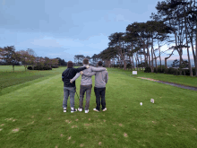 three men are standing on a golf course with their arms around each other and one of them has a golf club in his hand