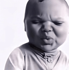 a black and white photo of a baby making a funny face with his eyes closed