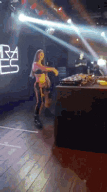 a woman is dancing in front of a dj booth in a club .