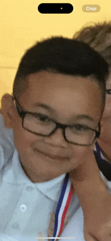 a young boy wearing glasses and a medal with the word crop on the bottom right