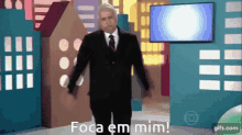 a man in a suit and tie is standing in front of a screen that says ' foca em mim '