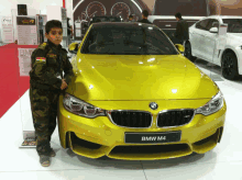 a young boy standing next to a yellow bmw m4