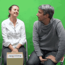 a man and a woman are sitting in front of a green screen with a box that says france inter