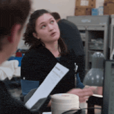 a woman in a black scrub top holds a piece of paper that says ' i 'm sorry '