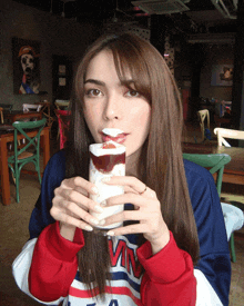 a woman wearing a calvin klein sweatshirt is drinking from a glass