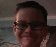 a young boy wearing glasses is smiling and making a face .