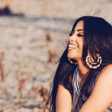 a woman wearing hoop earrings is smiling and looking to the side