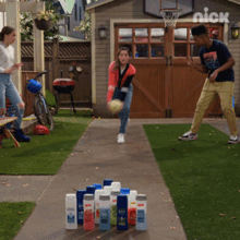 a boy and a girl are playing a game of bowling in front of a basketball hoop that says nick on it