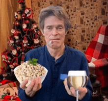 a man smoking a cigarette and holding a bowl of popcorn and a glass of wine