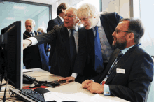 three men are looking at a computer screen and one of them has a name tag that says ' robert ' on it