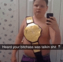 a young boy is taking a selfie with a wrestling championship belt around his waist .