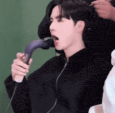 a person is blow drying another person 's hair with a hair dryer