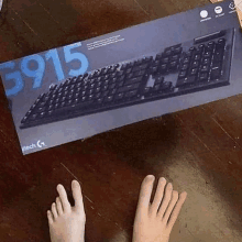 a person 's feet are laying on a wooden table next to a logitech keyboard box .