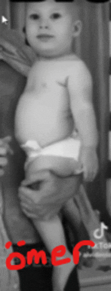 a black and white photo of a baby being held by a person with omer written in red