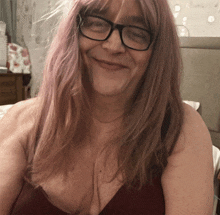 a woman wearing glasses and a red bra smiles for the camera