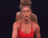a woman in a red tank top has a cross necklace